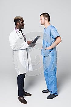 Two doctors meeting and consulting each other on gray background. Caucasian doctor and afroamerican doctor talking abount pacient