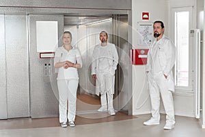 two doctors and a nurse stand at an elevator