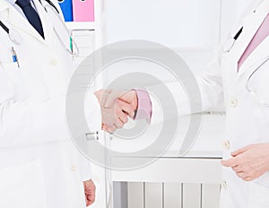 Two doctors shake hands in office. Medical insurance. Healthcare concept. Copy space