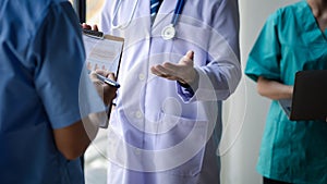 Two doctors stand in a conference room discussing, brainstorming on how to plan a patient's treatment in a complex case that