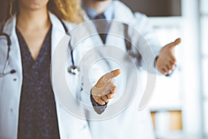 Two doctors standing and offering helping hand for shaking hand or saving life. Medical help, countering viral infection