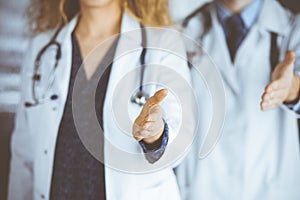 Two doctors standing and offering helping hand for shaking hand or saving life. Medical help, countering viral infection