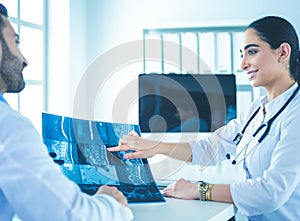 Two doctors studying x-ray image, consulting in bright office