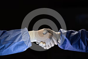 Two doctors in surgery cloth with rubber gloves shaking hands with team confident before start to do cure operation in dark