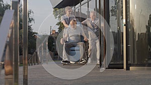 Two doctors take elderly man to the clinic on wheelchair