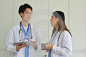 Two doctors talking to each other, analyzing results of patients medical examination at medical office