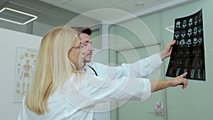 Two doctors, woman and men in medical apparel, discussing patient& x27;s x-ray tomography scan. Health care , medical and