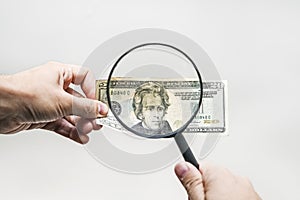 Two dollar bill and magnifying glass on white