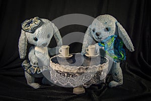 Two dolls leverets drinking tea at the table.