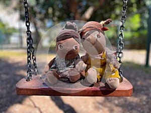 Two dolls on a swing on a sunny summer day.