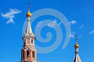 Two domes of orthodox church with golden crosses against the blue sky