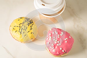 Two donuts in glaze and a paper coffee cup/two donuts in glaze a
