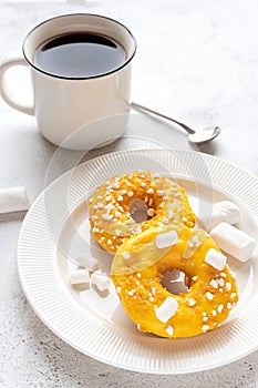 Two donuts with marshmallows and a cup of tea or coffee
