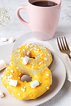 Two donuts with marshmallows and a cup of tea or coffee