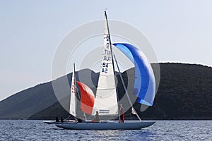 Two dragon boats with colored spinnaker sailing and competing for Dragon Cup in Bodrum, Turkey