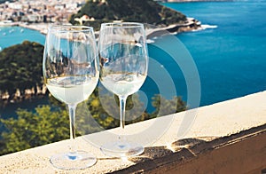 Two drink glass white wine standing on background blue sea top view city coast yacht from observation deck, romantic toast