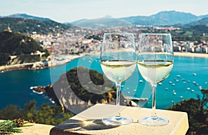 Two drink glass white wine standing on background blue sea top view city coast yacht from observation deck, romantic toast
