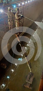 Two drydock worker washing ship for painting