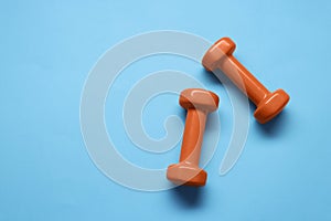 Two dumbbells on light blue background, top view. Space for text