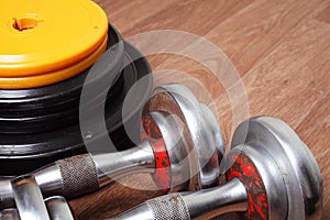 two dumbbells are lying on the floor next to the bar disks in the gym.