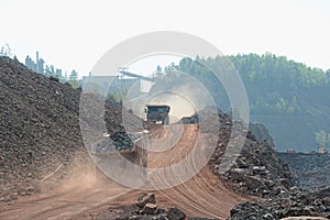 Two dumper trucks with loaded stones driving along in a quary. m