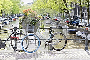 Two Dutch bikes are standing on the bridge on the spring day in Amsterdam. Typical spring Dutch landscape