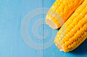 Two ears of boiled appetizing corn on a blue table/Two ears of boiled appetizing corn on a blue table. Healthy food. Top view and