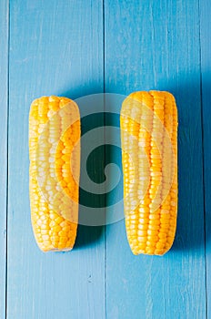 Two ears of boiled appetizing corn on a blue table/Two ears of boiled appetizing corn on a blue table. Healthy food. Top view