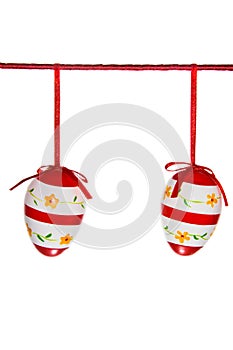 Two easter eggs hanging on a red