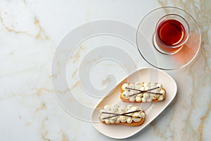 Two eclairs with white custard on whhite plate close up