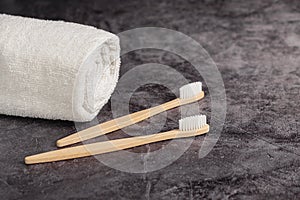 Two eco natural bamboo toothbrushes and white towel on grey background. Sustainable lifestyle and zero waste home.