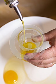 Two egg yolks with white yellow sugar oil and lemon peel in a red bowl for cake preparation