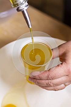 Two egg yolks with white yellow sugar oil and lemon peel in a red bowl for cake preparation