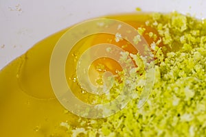 Two egg yolks with white yellow sugar oil and lemon peel in a red bowl for cake preparation