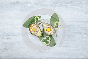 Two Eggs baked in avocado on wooden tabel and green leaves