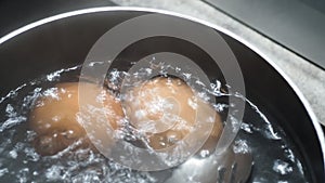 Two eggs in boiling hot water. Then one is spooned out for serving.