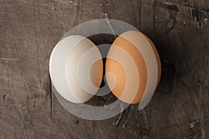 Two eggs, white and brown on a dark background.