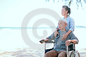 Two elderly couples happily sit in a wheelchair on the beach on their vacation