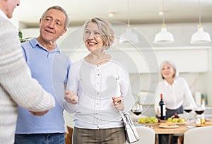 Two elderly couples meet for holiday dinner at home. Greet each other