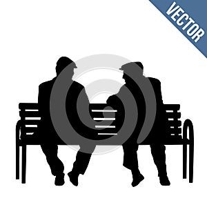 Two elderly people silhouettes sitting on a park bench