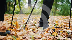 Two elderly women are doing Scandinavian walking in the park. Feet. Autumn