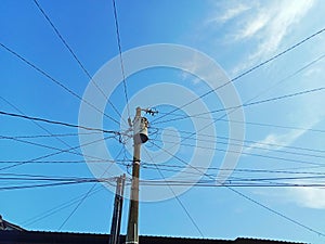 two electric poles and tubes. Electrical cables stretch against the background of a cloudy blue sky