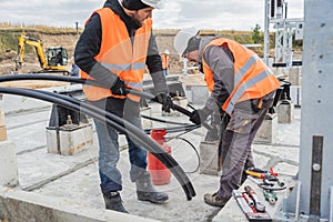 Two electrician builder workers installing high-voltage cable