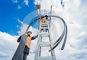 Two electrician builder workers installing high-voltage cable