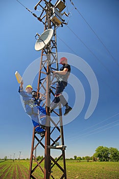 Two electricians install telecommunications antenna system