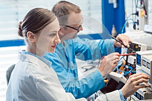 Two electronic engineers on the test bench measuring a new product photo