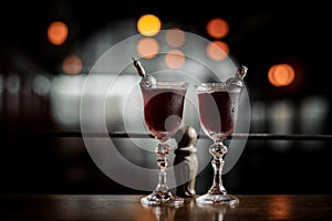 Two elegant glasses filled with fresh sweet and strong summer Arnaud cocktail on the dark blurred background