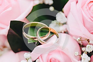 Two elegant gold rings for the wedding of lovers with scenery from fresh roses.