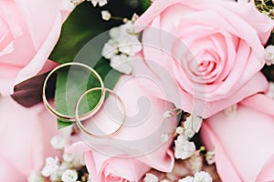 Two elegant gold rings for the wedding of lovers with scenery from fresh roses.