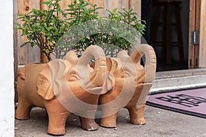 Two elephant cartoon shape redware flowerpots at the door of the house.
